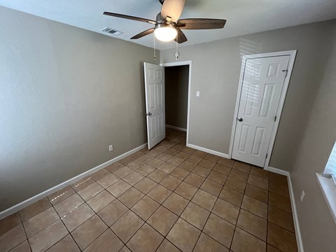 a empty living room with tiled floors and a ceiling fan