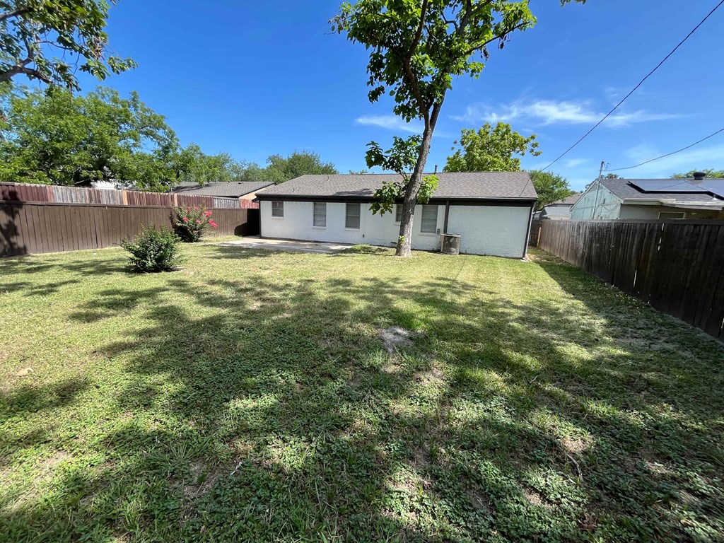 a backyard with a house and a yard with a tree
