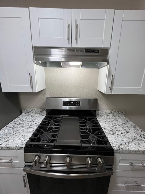 A modern kitchen with a stove top oven and white cabinets.