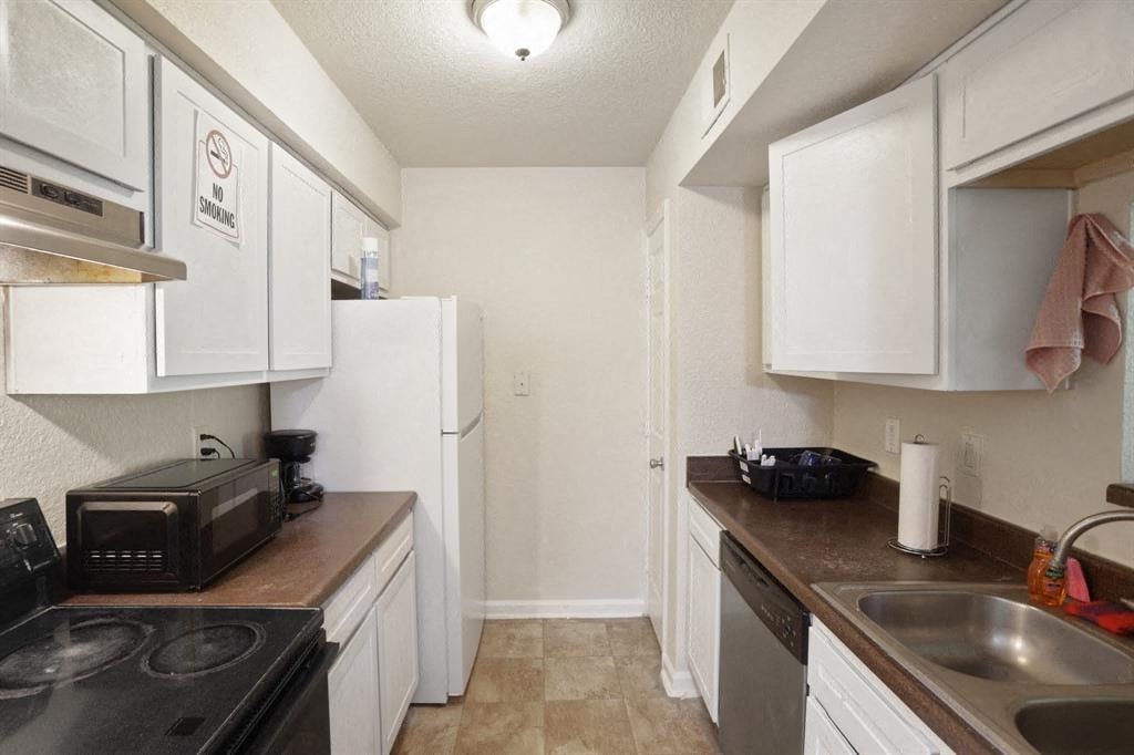 a kitchen with white cabinets and a sink and a refrigerator