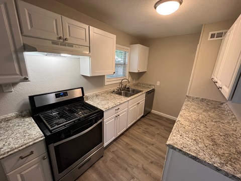 A kitchen with a black stove top oven and white cabinets.