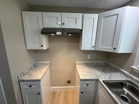 A kitchen with white cabinets and a marble countertop.