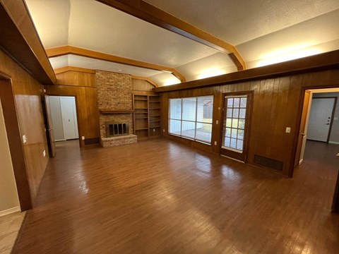 A room with wooden floors and a stone fireplace.