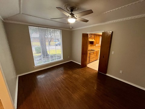 A room with a ceiling fan and wooden flooring.