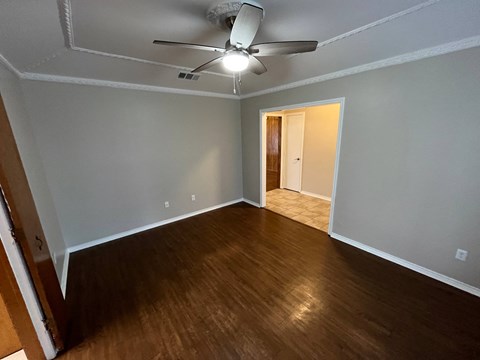A room with a ceiling fan and wooden flooring.