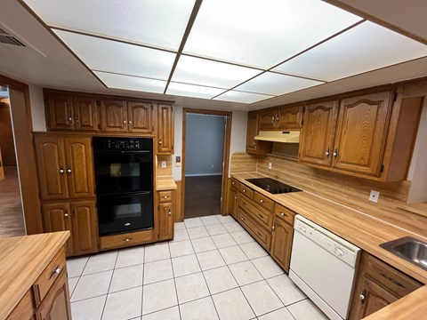 A kitchen with wooden cabinets and a black oven.