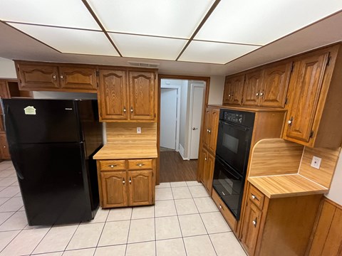 A kitchen with wooden cabinets and a black refrigerator.