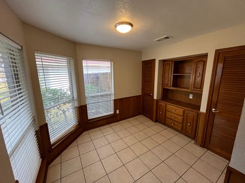 A room with a tiled floor and wooden cabinets.