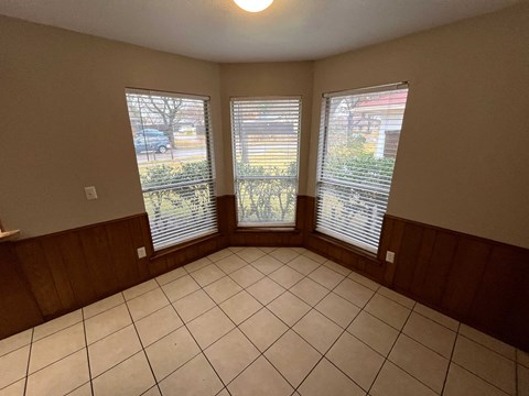 A room with a tiled floor and a window with blinds.