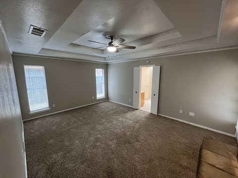 A room with a carpeted floor and a ceiling fan.