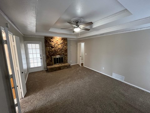 A room with a carpeted floor and a ceiling fan.