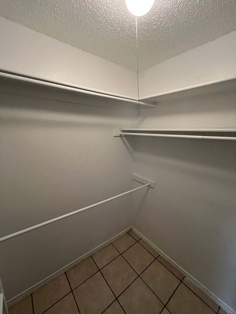 A white wall with a light on and a tiled floor.