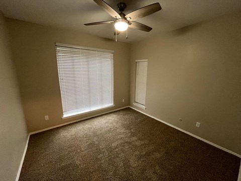 A room with a ceiling fan and carpeted floor.