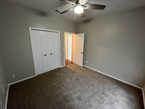A room with a ceiling fan and two doors.