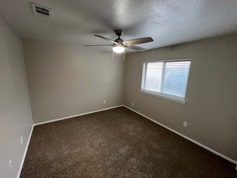 A room with a ceiling fan and carpeted floor.