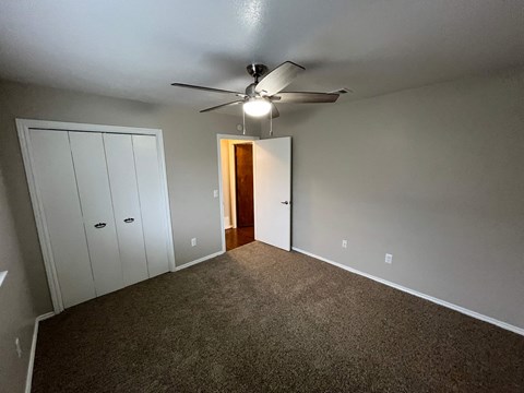 A room with a ceiling fan and carpeted floor.