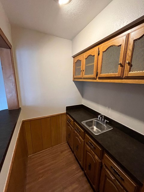A kitchen with wooden cabinets and a black countertop.