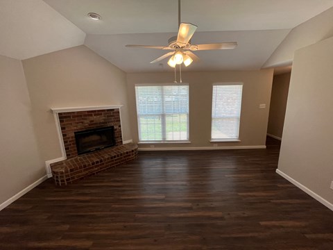 A living room with a fireplace and a ceiling fan.