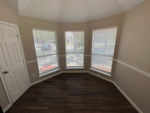 A room with a white door and two windows with blinds.