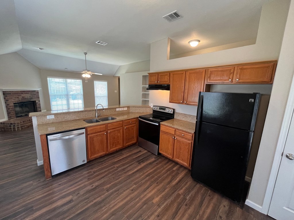 A kitchen with wooden cabinets and a black refrigerator.
