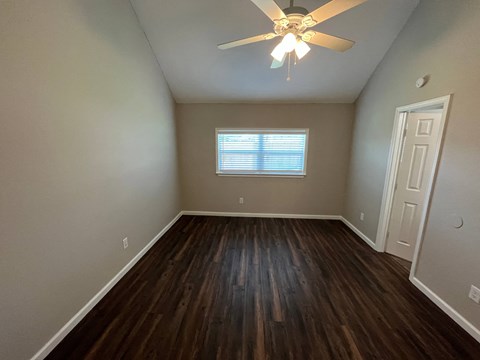 A room with a ceiling fan and wooden flooring.