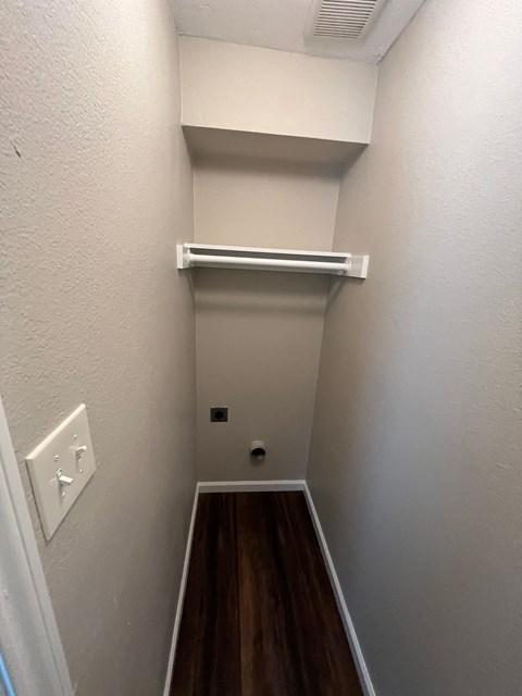 A long, narrow hallway with a white wall and a light switch.