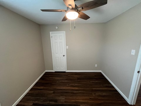 A room with a ceiling fan and a door.