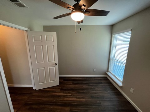 A room with a ceiling fan and a door.