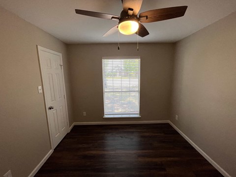 A room with a ceiling fan and a window with blinds.