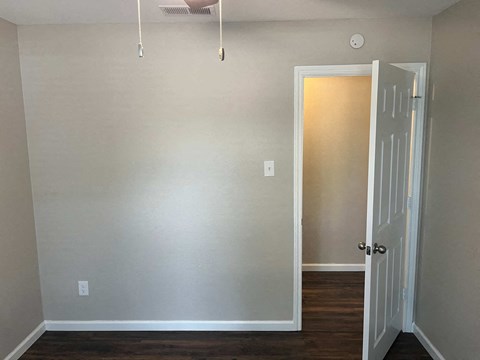 A room with a white door and a ceiling fan.