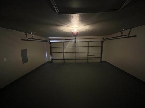 A dimly lit garage with a light on and a door in the middle.