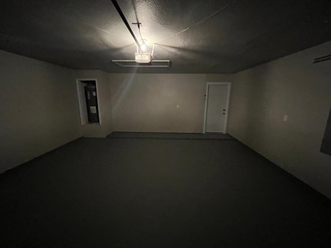 A small, dark room with a door and a light on the ceiling.