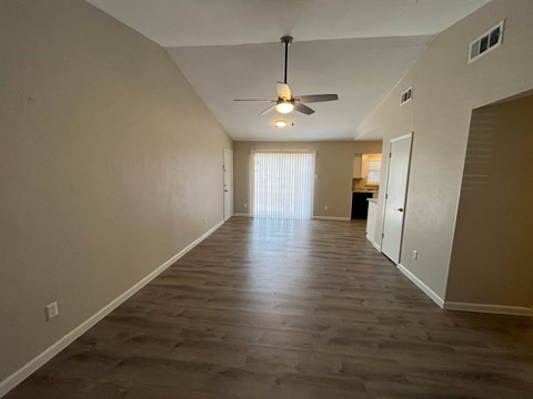 A long, empty hallway with a ceiling fan and light fixture.