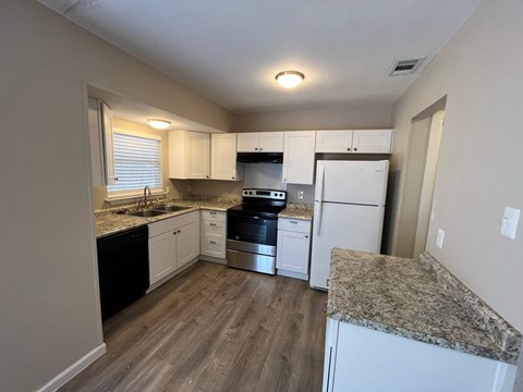 A kitchen with a granite counter top and white appliances.