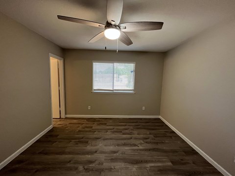 A room with a ceiling fan and wooden flooring.