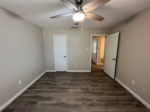 A room with a ceiling fan and two doors.