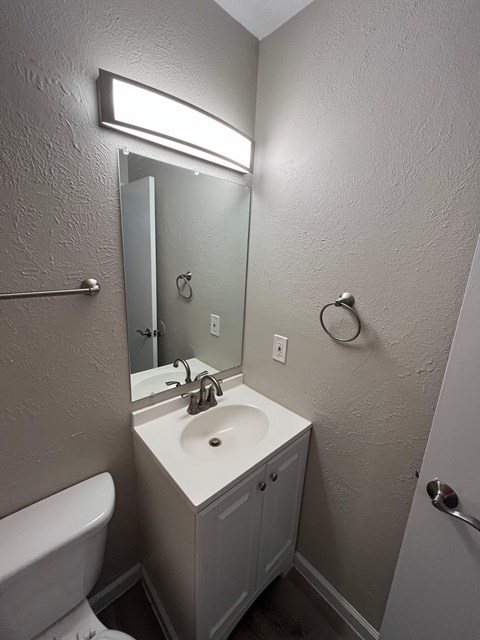 A small bathroom with a toilet, sink and mirror.