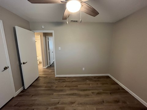 A room with a ceiling fan and wooden flooring.