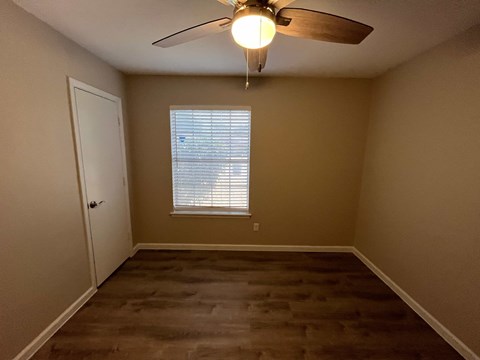A room with a ceiling fan and a window with blinds.