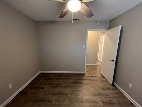 A room with a ceiling fan and a door leading to another room.