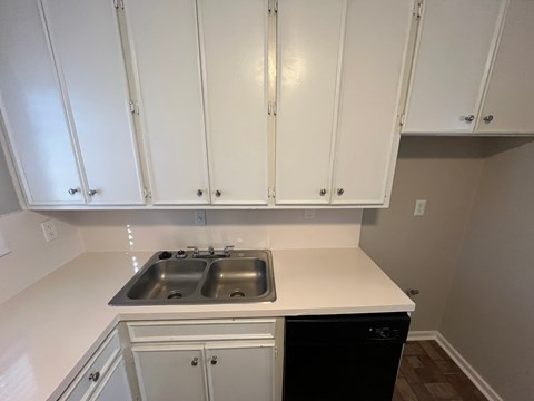 A kitchen with white cabinets and a black dishwasher.
