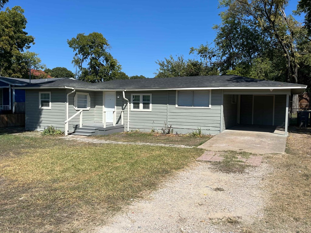 A house with a grey exterior and a white door is surrounded by trees.