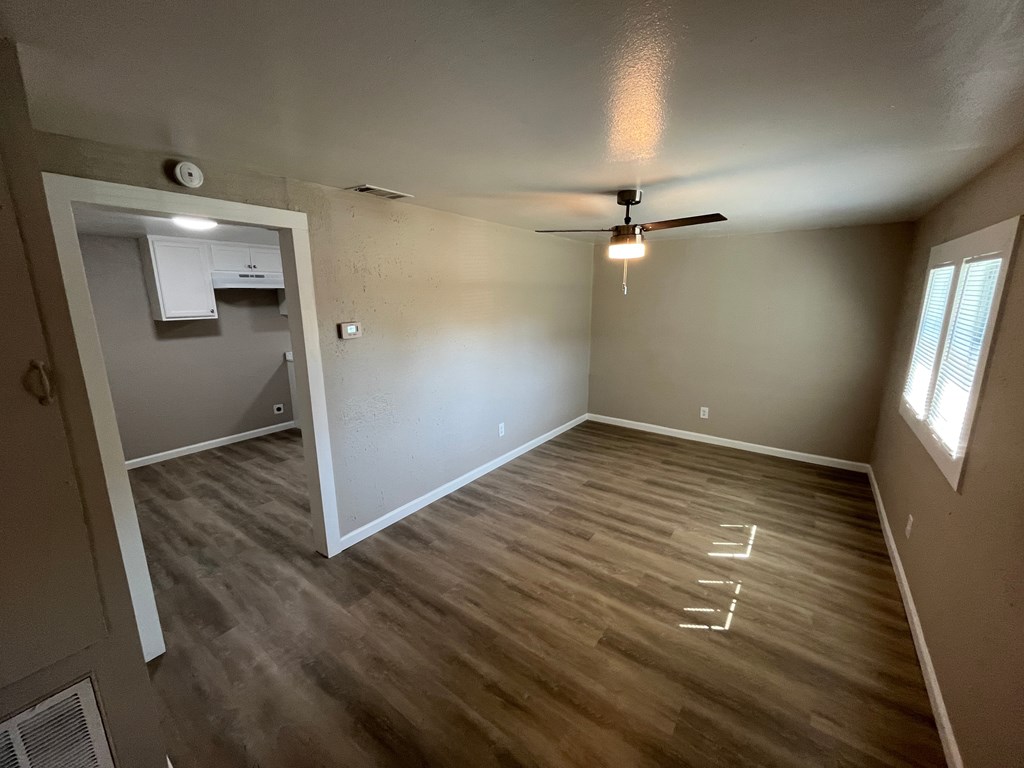 A room with a ceiling fan and a window with blinds.