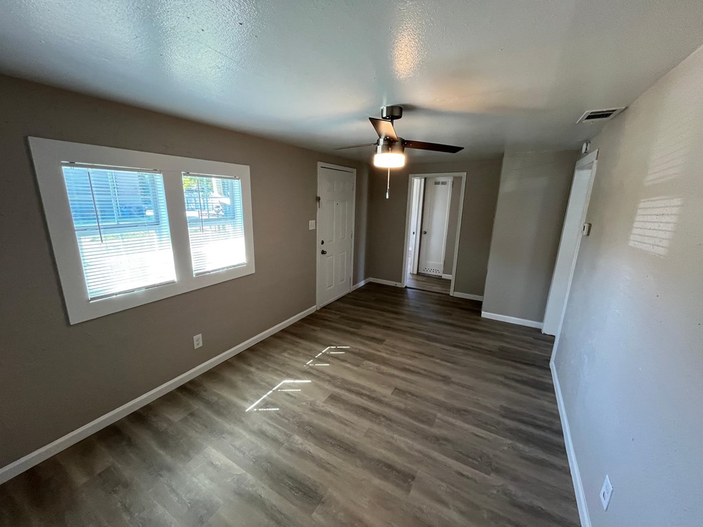 A room with a ceiling fan and wooden flooring.