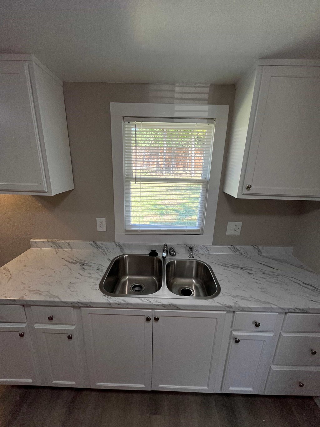 A kitchen with a marble countertop and white cabinets.