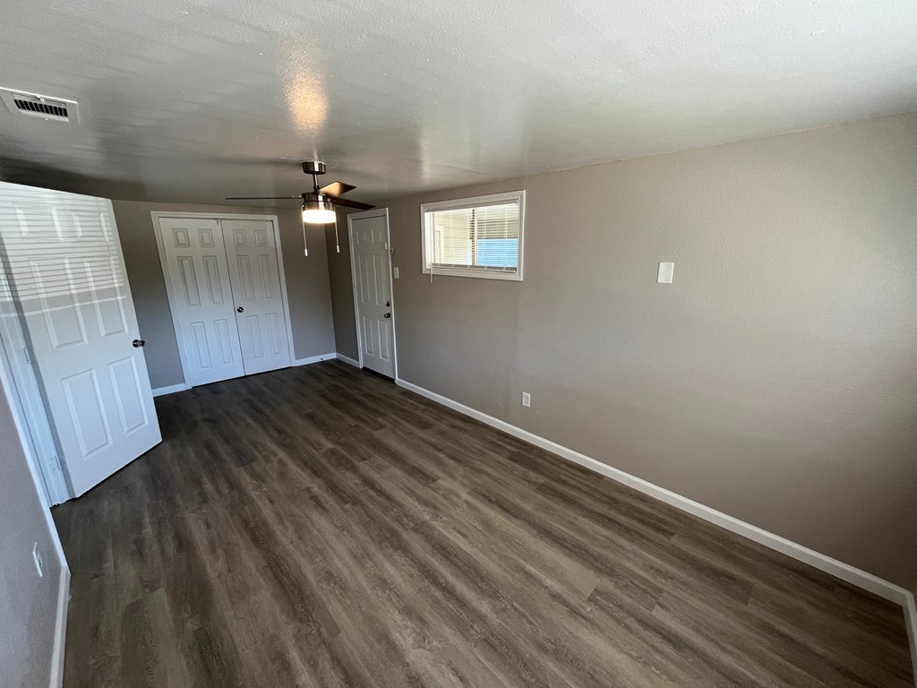 A room with a ceiling fan and wooden flooring.