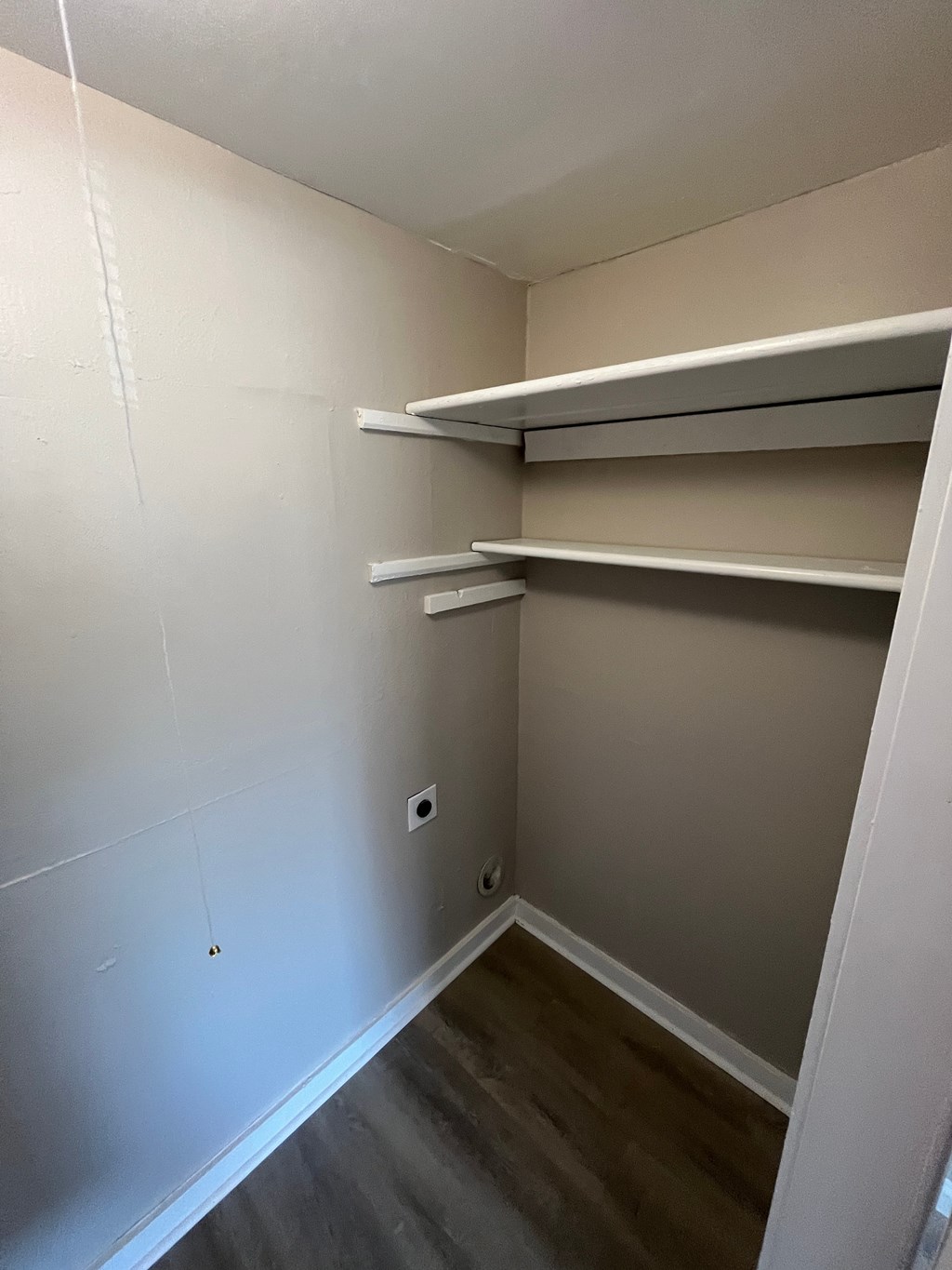 Empty room with shelves and a light switch on the wall.