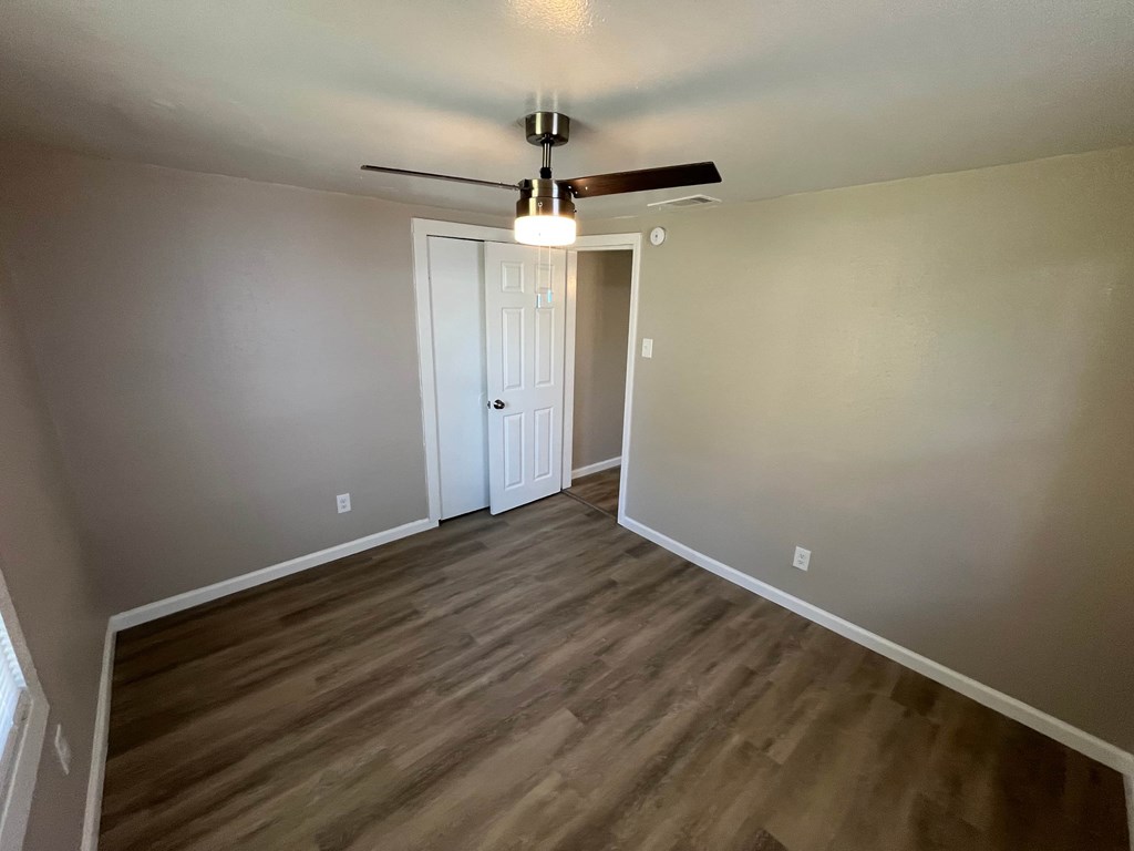 A room with a ceiling fan and wood flooring.
