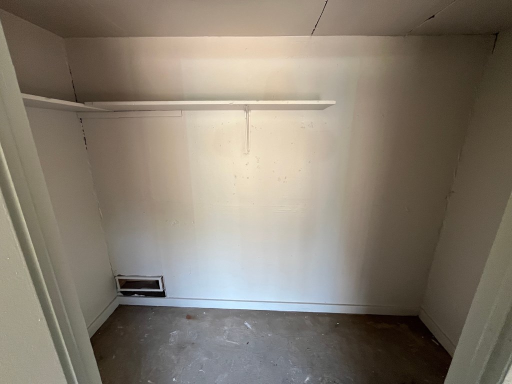 A white wall with a shelf and a drainage pipe.