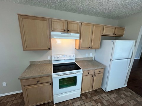 A kitchen with a white stove top oven and white refrigerator.